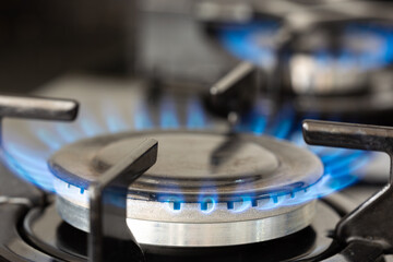 Close up blue fire from domestic kitchen stove top. Gas cooker with burning flames of natural gas....