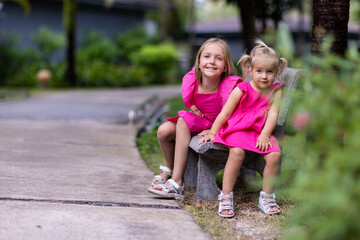 Candid lifestyle portrait of cute little Caucasian sisters nine years old and two years old with...