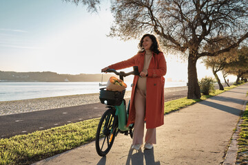 Pregnant woman in orange coat on electric bicycle on the promenade at sunset  © stockmaster