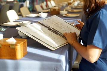 A Thai woman in a restaurant while waiting for friends to have dinner together. She chooses a menu and orders food that she and her friends like before friends arrive so they can eat.