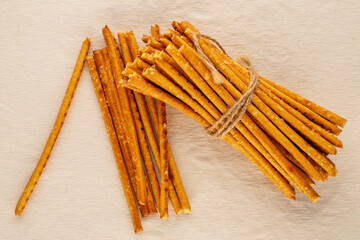 Straw is a bakery product. A few straws on a white linen cloth, macro, top view.