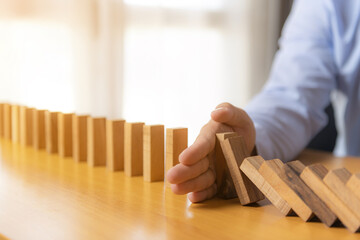 Protection finance from domino effect concept. Hands stop domino effect before destroy stack of money.