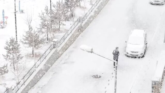 Aerial view of a man trekking through heavy snow, leaving a trail of footprints