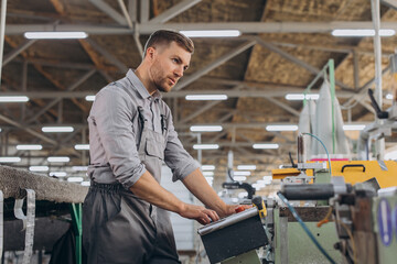 Factory male bearded worker is programming a CNC milling machine with copy space.