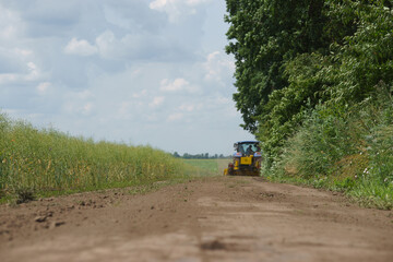 Grader works with tractor and levels the field road