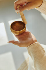 Closeup of woman hands using singing bowl in sound healing therapy.