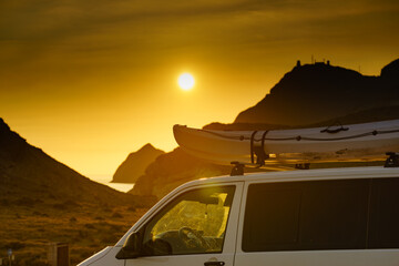 Fototapeta na wymiar Canoe on top roof of car at sunset