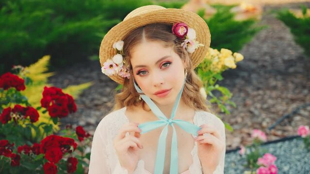 art portrait fashion model adult girl princess sitting in summer nature roses garden, straw hat flowers in long hair cute baby doll face. Young woman red lips green eyes fantasy vintage retro style 4k
