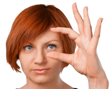 Woman looking at something she is holding between her thumb and index finger - isolated image