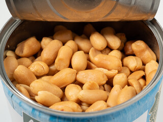 Roasted peanuts in an open jar on orange. Peanuts close up.