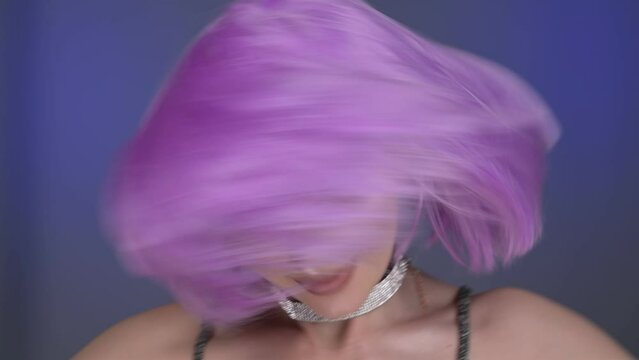 A gorgeous girl in a violet wig poses in the studio. Portrait. Colorful background. 4K, 30fps