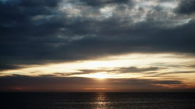 Seascape at early morning. Time lapse of dark stormy clouds moving over sea at sunrise. Nature landscape in Spain.