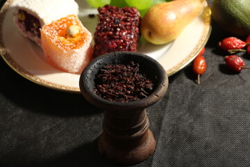bowl of tobacco for hookah. smoking shiisha. berries and fruits on a dark background