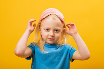 Portrait of child with eye mask on yellow background. Little blonde girl takes off the sleep mask...