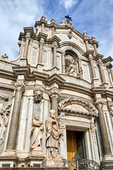 Fototapeta na wymiar Columns and statues of the Baroque facade of the Cathedral Basilica of St. Agates in the city of Catania, on the island of Sicily