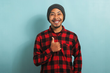 Asian man with beanie hat and red plaid flannel shirt showing thumb up - Powered by Adobe