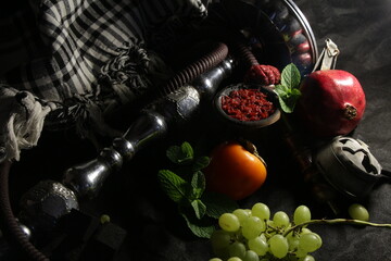 Obraz premium bowl with tobacco for hookah. nargile smoking. berries and fruits on a dark background.