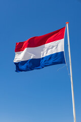 Fototapeta na wymiar Waving Dutch flag in front of a blue sky in The Netherlands