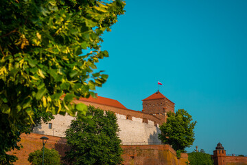 Southern part of Wawel castle in Krakow city, rising up from the green grass up towards the blue sky.. Wide panorama of famous castle