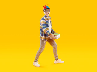 Funny school child carrying books. Full body shot of happy little boy in casual clothes, round...