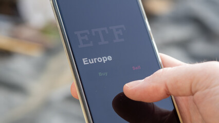 An investor looking at an Europe ETF on his smartphone. Investment in European funds on a screen.