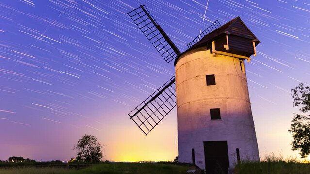 Time lapse of star trails in the night sky over windmill sails