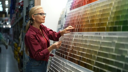 Woman looking at paint chips in a hardware store. Concept of home remodeling shopping experience.