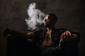 Handsome tattoo young man smoking in loft room