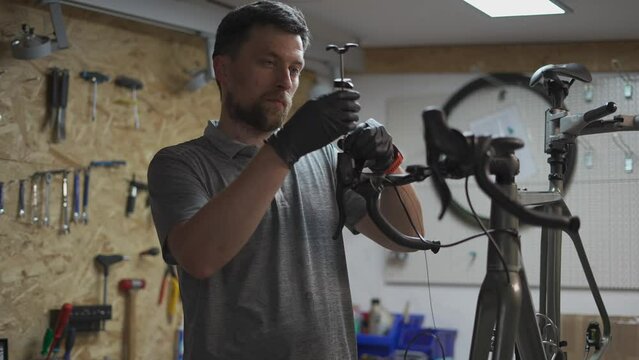 Bicycle mechanic holding syringe with brake fluid during brake bleeding process. Cycle repairman injects brake fluid into hydraulic brakes on bike in workshop. Maintenance cycle brake disc system. 