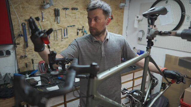 Bicycle mechanic holding syringe with brake fluid during brake bleeding process. Cycle repairman injects brake fluid into hydraulic brakes on bike in workshop. Maintenance cycle brake disc system. 