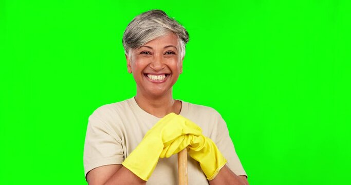 Face, senior woman and cleaner, green screen and happy housekeeper with broom and gloves on studio background. Cleaning service, female maid and house work with mockup space, smile and hygiene