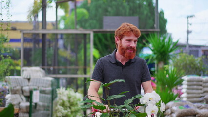 Happy Young Man with Shopping Cart exploring Aisle in Horticulture Store. Male Customer Shopping for Plants at Local Garden Shop