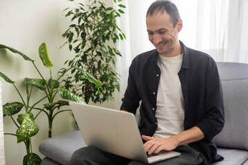 Happy smiling deaf young caucasian man uses sign language while video call using laptop while sitting at home, virtual communication concept.