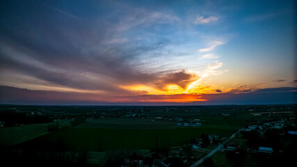 Drone View of a Red Sunset, Peaking Thru Clouds, Looking Over Rural Countryside, and Farmlands