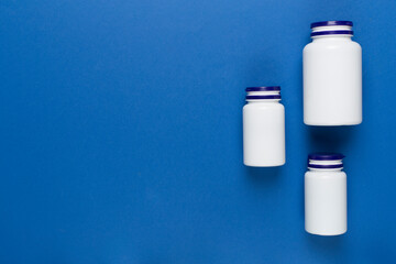 Plastic bottles with vitamins on color background, top view