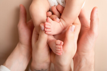 Obraz na płótnie Canvas hands of parents and children on a white background. legs of a newborn in the hands of mom and dad. baby feet in hands