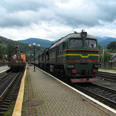 Obraz premium A passenger train approaches the mountain railway station