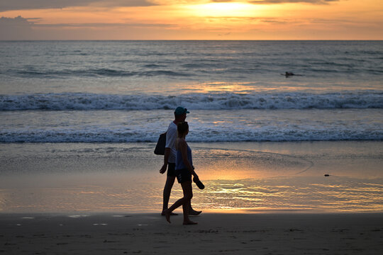 A young couple walking on the beach of Phuket-Thailand in the sunset.