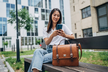 Young Japanese woman reading a message on the mobile phone in the city