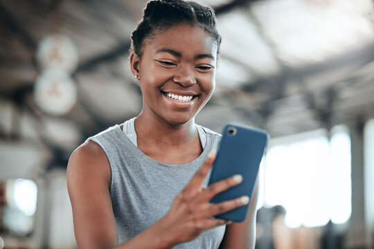 Social media, happy or black woman with phone in gym to search for a sports blog in training or exercise. Fitness app, smile or healthy girl athlete relaxing or reading online mobile content on break