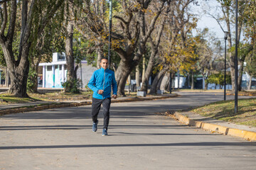 Fototapeta na wymiar Latino man runs by a public park.