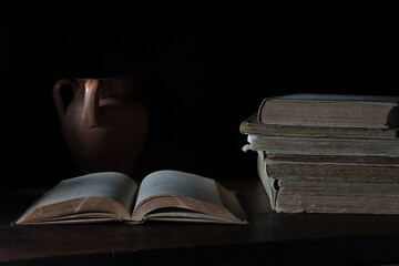 open book close-up together with other books on writing desk