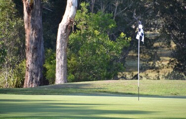 Golf course with flagstick in the morning