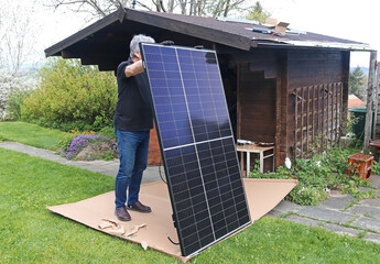 Ein Mann möchte eine kleine Solaranlage auf einem Gartenhaus montieren