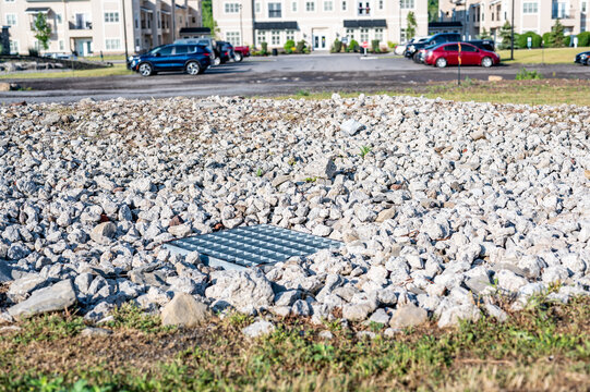 Grated storm drain inlet surrounded by rock for soil erosion control 
