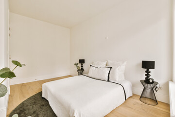 a bedroom with white walls and hardwood flooring in the room, it is well lit by the light coming through the window