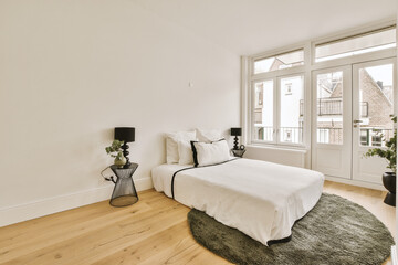 a bedroom with white walls and hardwood flooring in the middle of the room, there is a large window that looks out into