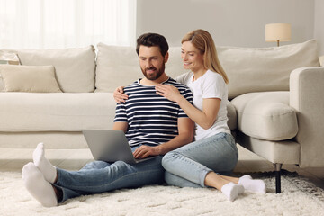 Obraz premium Happy couple with laptop on floor at home