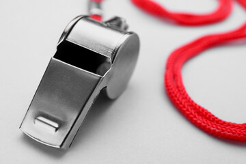 One metal whistle with red cord on white background, closeup