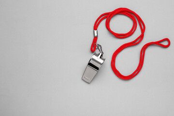 One metal whistle with red cord on light grey background, top view. Space for text